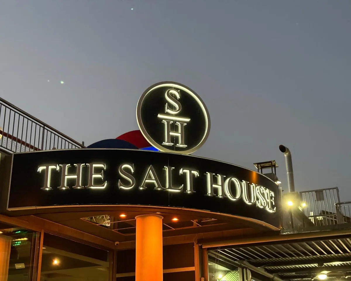 The round S|H sign lit above the entrance at dusk
