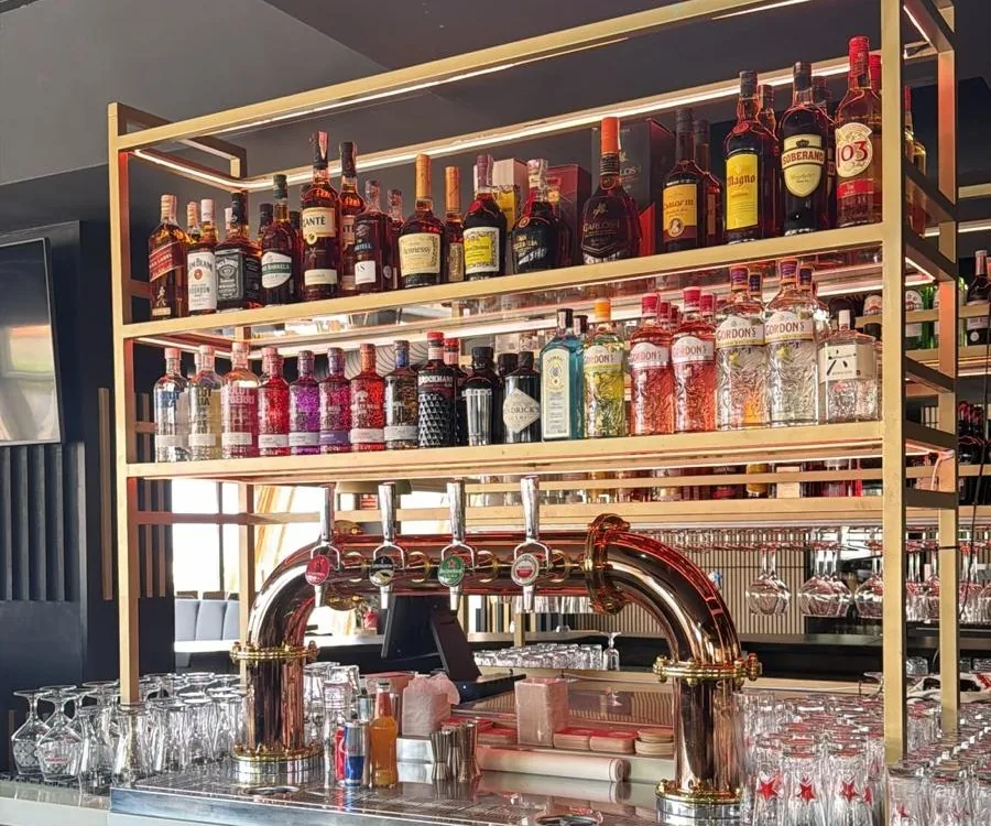 The back bar: gold shelving lined with bottles above the beer taps