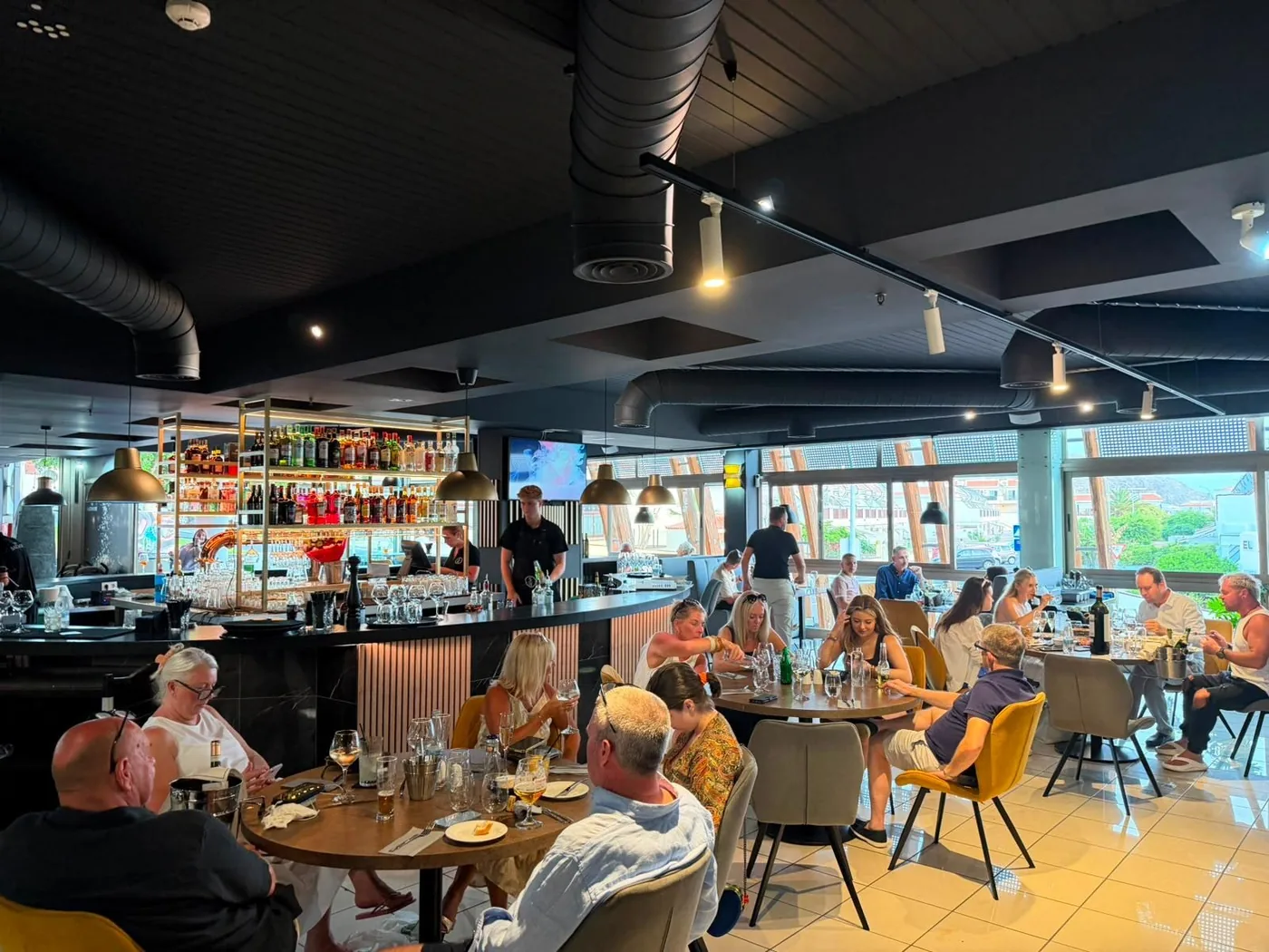 The dining room full of guests, with the bar and its gold shelving at the back